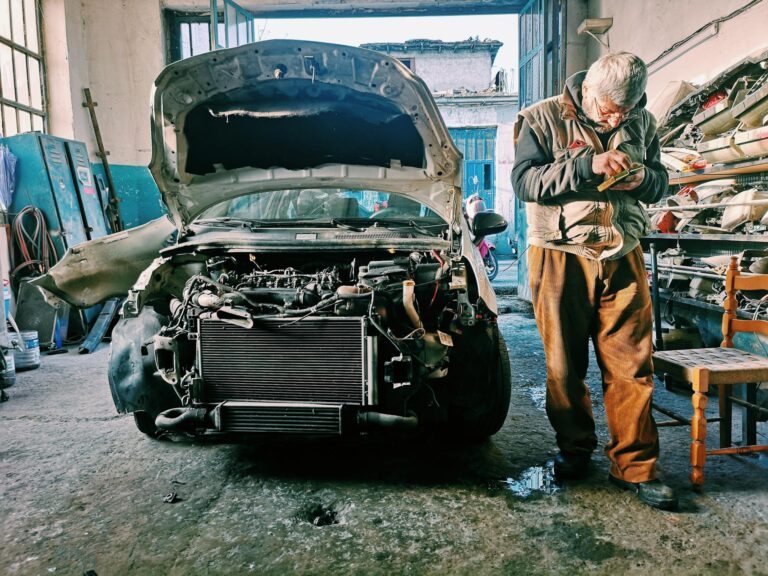 Mechanic repairing car in an auto workshop with the hood open showcasing the engine.